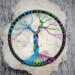 small tree is displayed against q chunk of quartz crystal showcasing the colorful tree